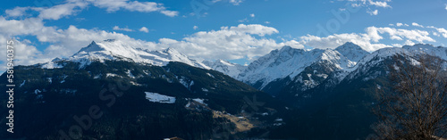 Panorama of snowy mountain peaks above a valley with forests in winter in the Austrian Alps.