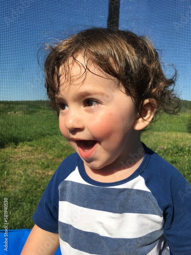 funny curly playful little child smiles cheerfully laughing with his mouth open