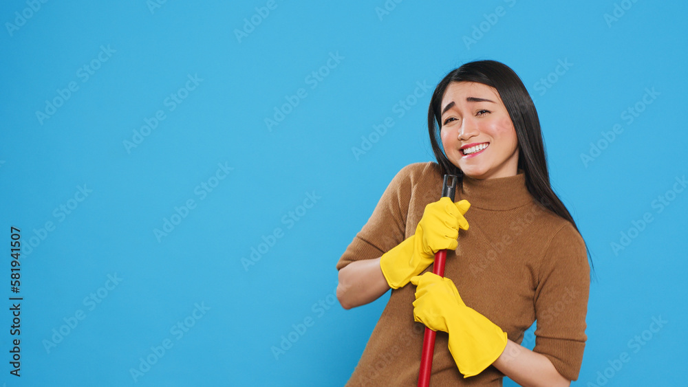 Happy housekepper dancing and having fun in studio while doing housecleaning using broom, dedicated to providing top-notch cleaning services to her clients. Housekeeping concept. Happy housekepper dancing and having fun in studio while doing housecleaning using broom, dedicated to providing top-notch cleaning services to her clients. Housekeeping concept.