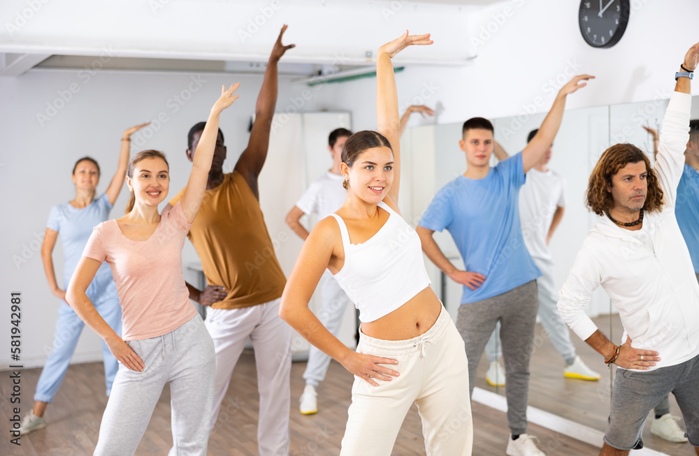 Fototapeta premium Active women and men dancing synchronous group choreography in dance hall