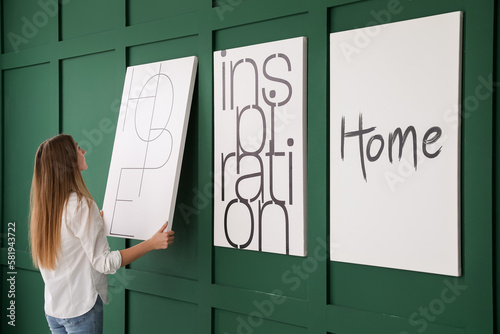 Young woman hanging poster ...
