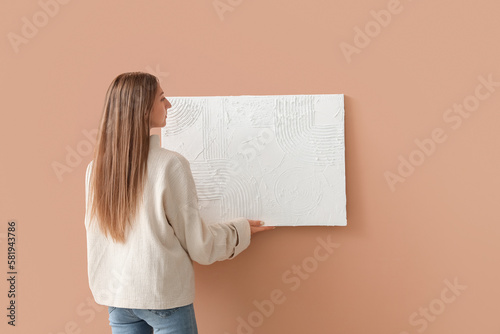 Young woman hanging paintin...