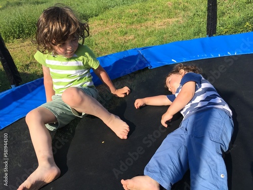 two curly brothers play and relax sit and lie on the trampoline