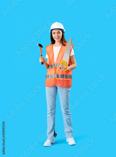 Female worker in vest and with tools on blue background