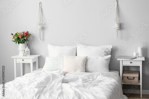 Stylish interior of light bedroom with alstroemeria flowers photo