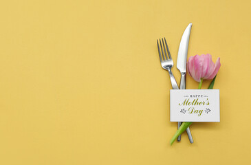 Greeting card with text HAPPY MOTHER'S DAY, cutlery and tulip flower on yellow background