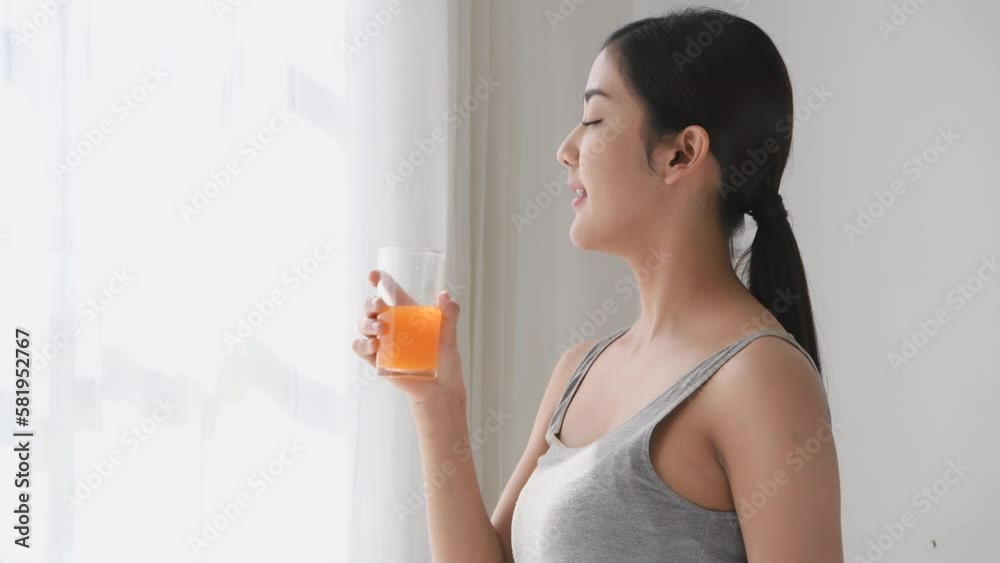 Holiday concept of 4k Resolution. Asian woman drinking orange juice after exercising at home.
