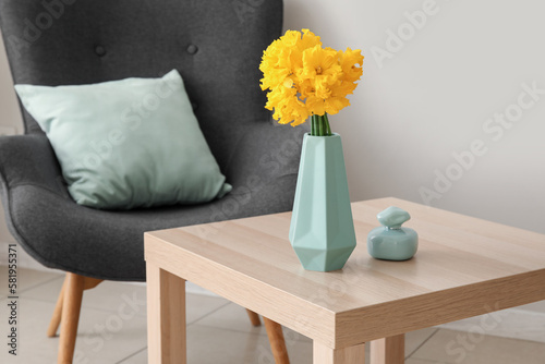 Vase with narcissus flowers and perfume on table in living room