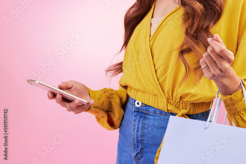 Phone, shopping bag and woman hands isolated on pink background for online shopping, ecommerce and retail. Fashion person on mobile app, cellphone or smartphone for discount, sale or promo in studio