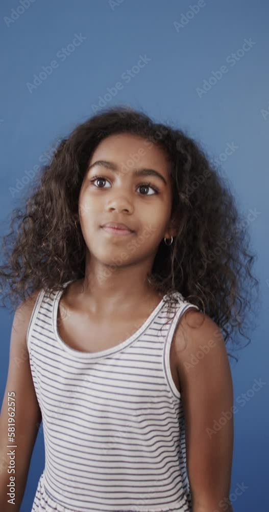 Vertical video of happy biracial girl using sign language on blue background, slow motion Vertical video of happy biracial girl using sign language on blue background, slow motion