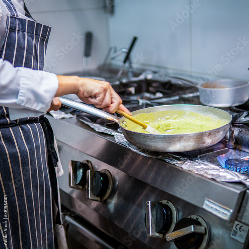 A chef cooking food in a pan with a wooden handle.