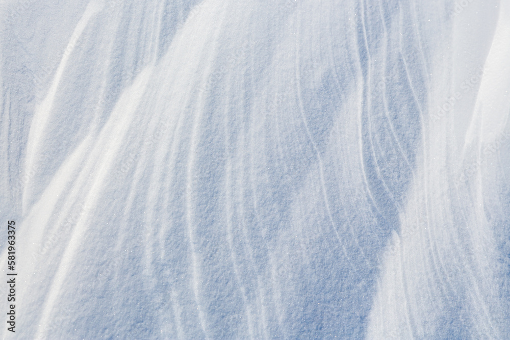 Obraz premium Beautiful winter background with snowy ground. Natural snow texture. Wind sculpted patterns on snow surface.