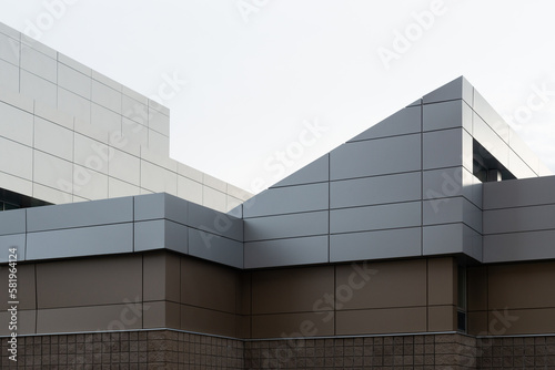 The exterior wall of a contemporary commercial style building with aluminum metal composite panels and glass windows. The futuristic building has engineered diagonal cladding steel frame panels. 