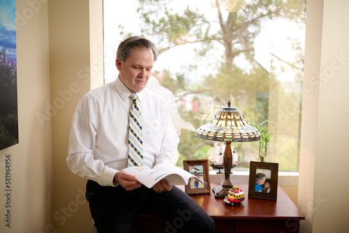 THE WOODLANDS, TEXAS - MARCH 2023: Jim Sloan, a wealth manager at Jim Sloan & Associates is posing for environmental business portraits in his office boasting views of a pine tree forest.