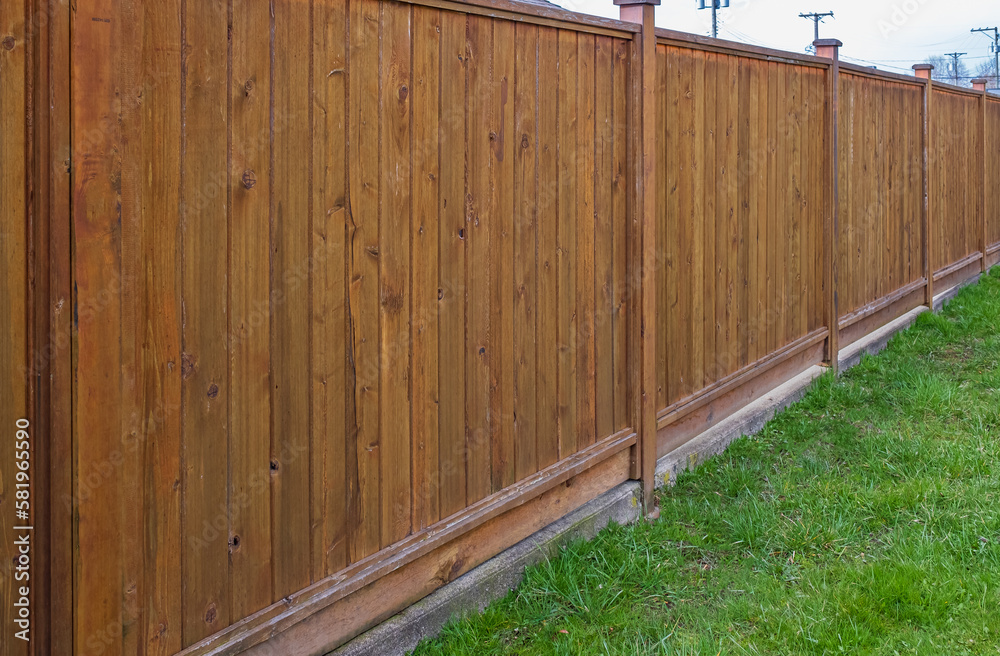 Nice new white wooden fence around house. Wooden fence with green lawn. Street photo