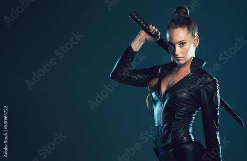 Woman, warrior and portrait with space in studio for action, fight and safety from danger on dark background. Strong female model or assassin in scifi leather cosplay costume and sword for action photo