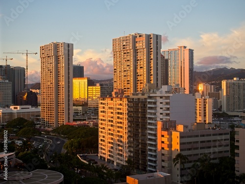 The high rise hotels of Honolulu s famous Waikiki neighborhood glow orange as the sun drops below the horizon