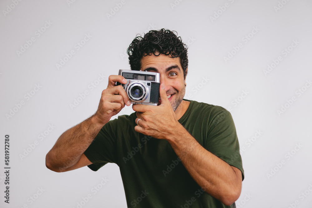 Middle-aged Latin man taking pictures with an old roll camera on a white background. Middle-aged Latin man taking pictures with an old roll camera on a white background.