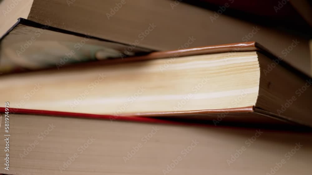 Close-up of a Stack of Colorful Old Hardcover Books in the Rays of Sunlight. Camera movement from top to bottom. Home collection of books. Daylight. The concept of learning, reading, and knowledge. Close-up of a Stack of Colorful Old Hardcover Books in the Rays of Sunlight. Camera movement from top to bottom. Home collection of books. Daylight. The concept of learning, reading, and knowledge.