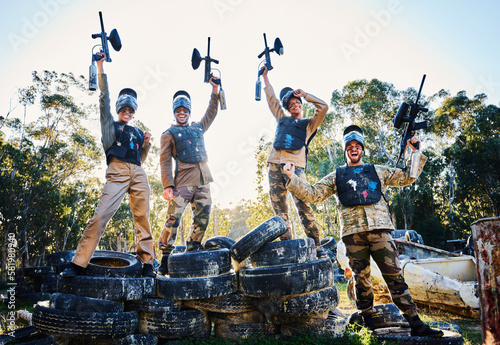 Team, paintball and portrait in celebration for winning, victory or achievement standing on tires together in nature. Group of people enjoying win, success or teamwork with guns in the air for sports