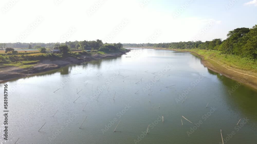 flying close over the Surma river with trees along the right side of the river and rice fields on the left in Sylhet, Bangladesh (shot moving from right to left) flying close over the Surma river with trees along the right side of the river and rice fields on the left in Sylhet, Bangladesh (shot moving from right to left)