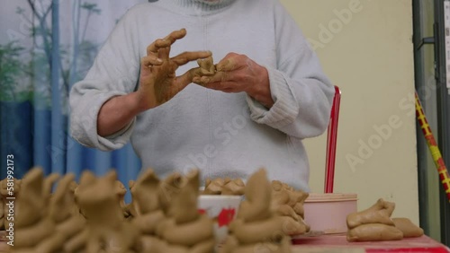 An Asian woman crafts animal figures in clay for souvenir flutes, showcasing Thanh Ha's tourism and traditional craftmaking in a front view shot. photo