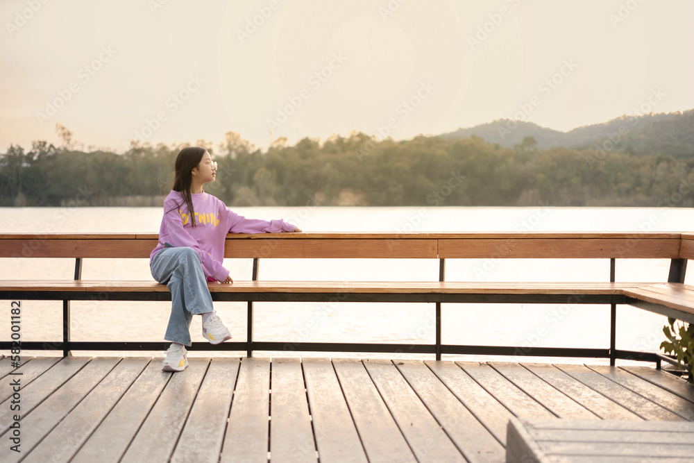 Asian girl sitting and enjoying the morning scenery by the lake with mountains