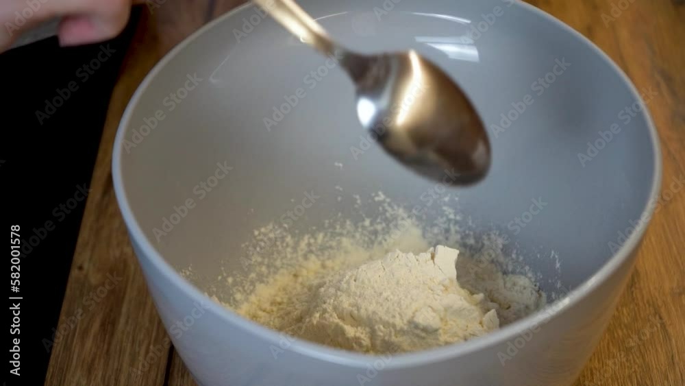 Woman Adding a Spoon of Flour to a Bowl Woman Adding a Spoon of Flour to a Bowl