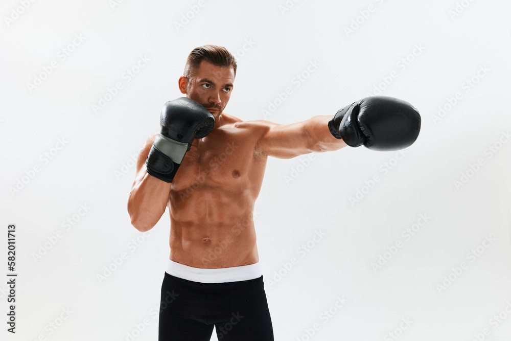 Man athletic bodybuilder poses in boxing gloves with nude torso abs in full-length background, boxing and martial arts. Advertising, sports, active lifestyle, light, competition, challenge concept. Man athletic bodybuilder poses in boxing gloves with nude torso abs in full-length background, boxing and martial arts. Advertising, sports, active lifestyle, light, competition, challenge concept.