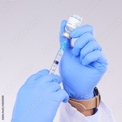 Hands, vaccine and healthcare with a doctor in studio on a gray background holding monkeypox treatment. Medical, innovation and insurance with a medicine professional ready to administer a cure