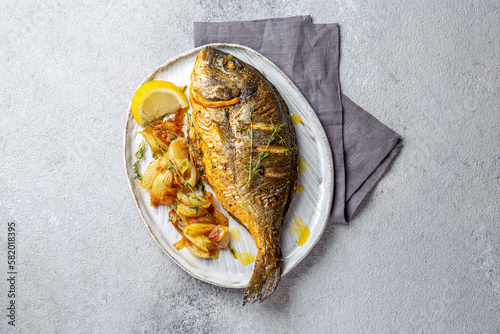 Grilled sea bream or dorada on gray plate. Gray background photo