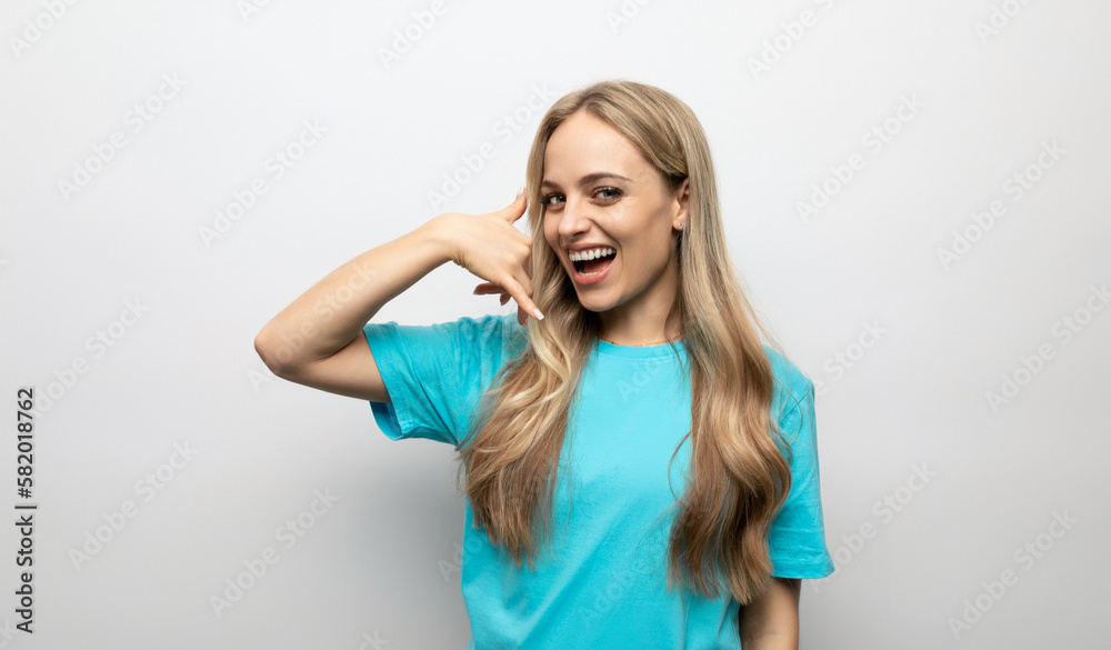 young woman showing phone gesture on white background