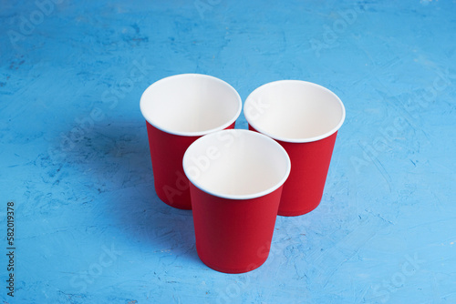 Three red disposable cups on a blue background. Place for text