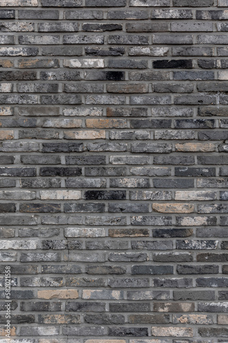 gray grey and black color stone wall texture background made of dark-colored bricks with a dull, old, rough and messy feel