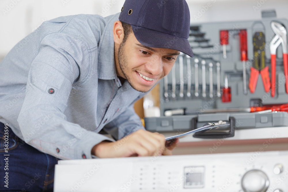 plumber installing washing machine in domestic bathroom plumber installing washing machine in domestic bathroom