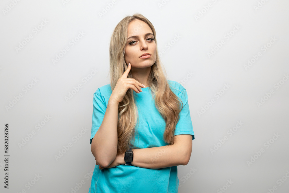 blond young woman looks thoughtfully at the camera on a white background blond young woman looks thoughtfully at the camera on a white background