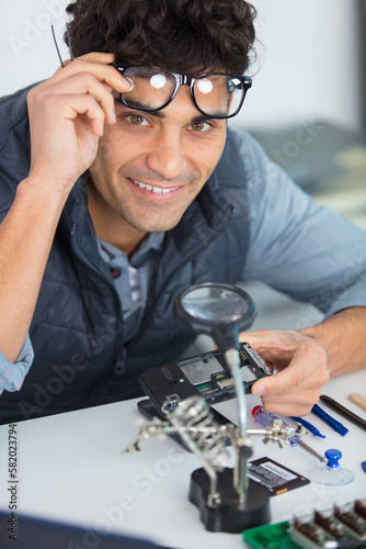 engineer soldering microcircuit though magnifier