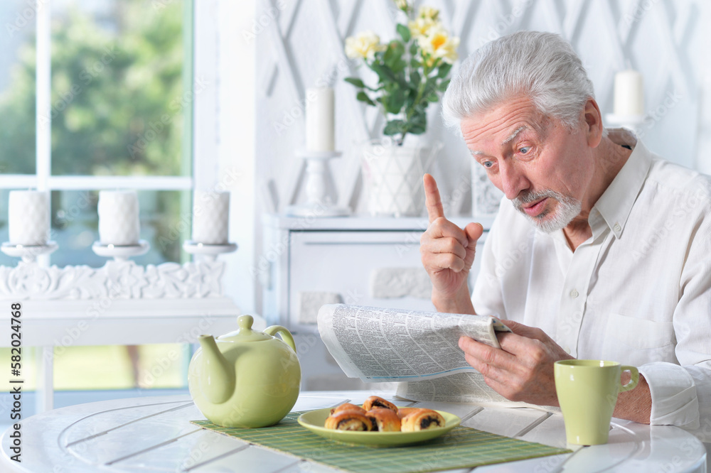 Emotional senior man reading newspaper