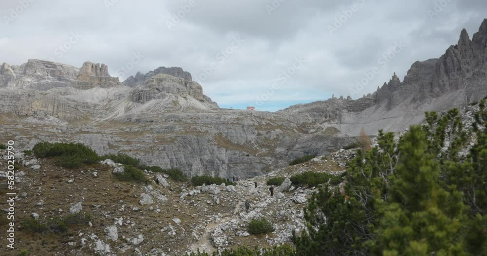 A stunning panning shot of Veneto's 3 Cime Lavaredo, with clouds floating above and hikers visible in the background. A stunning panning shot of Veneto's 3 Cime Lavaredo, with clouds floating above and hikers visible in the background.