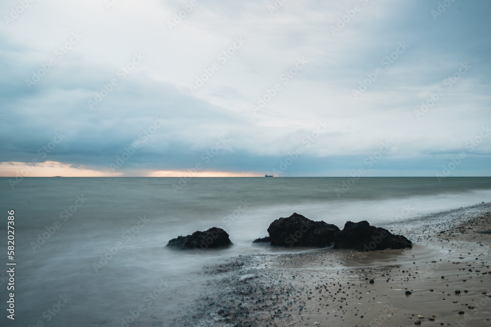 Long exposure shot of rocks in the calm sea on an overcast day