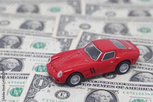 Small toy car on dollar banknotes in the form of a road  isolated on a white background  the cost of owning a car.