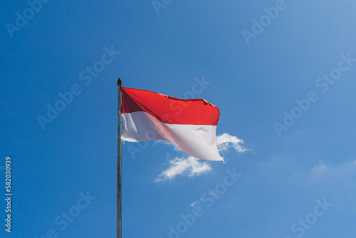 indonesia natonal flag "merah putih" fluttering with blue sky as a background