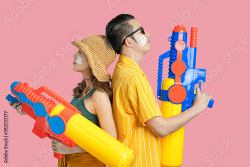 Photography Asian couple holding water guns colorful on pastel pink background