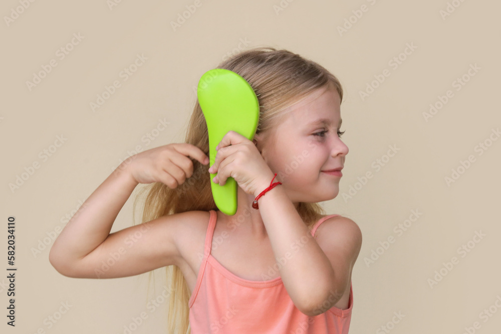 Candid portrait of cute little girl combing her long hair with detangler brush Candid portrait of cute little girl combing her long hair with detangler brush