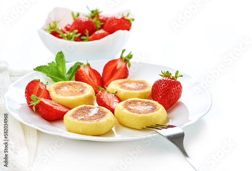 Cottage cheese pancakes  syrniki  ricotta fritters on ceramic plate with fresh strawberry.