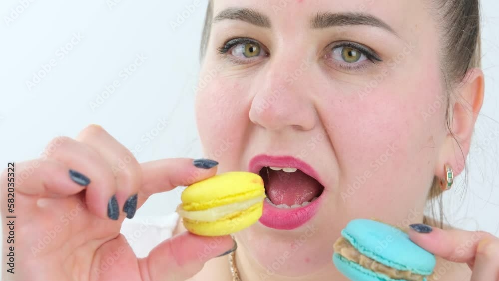 a fat plump woman eats a lot of delicious sweet macarons desserts smiles joyfully and opened mouth wide, gold jewelry on a white background, diet, overeating a fat plump woman eats a lot of delicious sweet macarons desserts smiles joyfully and opened mouth wide, gold jewelry on a white background, diet, overeating