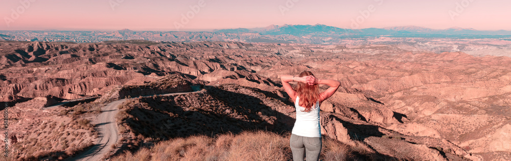 Woman standing and looking at sunset Gorafe desert in Spain