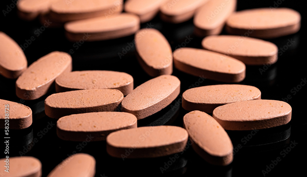 Close up of Multi Vitamin tablet on a reflective black backgroun Close up of Multi Vitamin tablet on a reflective black backgroun