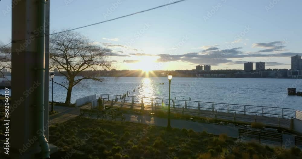 People riding bikes and walking on the coast of the Hudson river, sunrise in New York - Aerial view People riding bikes and walking on the coast of the Hudson river, sunrise in New York - Aerial view