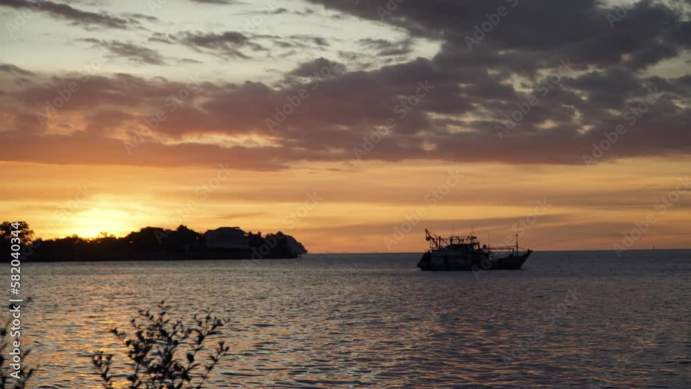 Silhouetted Docked Fisher Boat with Stunning Golden Sunset Background at Kota Kinabalu Waterfront. Sun Hides Behind Island horizon Silhouetted Docked Fisher Boat with Stunning Golden Sunset Background at Kota Kinabalu Waterfront. Sun Hides Behind Island horizon